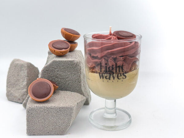 dessert soy candle on glass container next to grey stones with wax melts